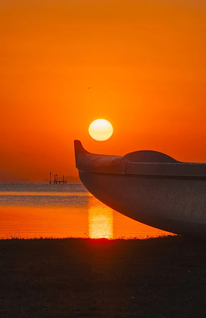 Proa de canoa havaiana recortada pelo sol poente na Laguna de Araruama